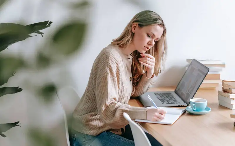 A professional taking notes beside a laptop
