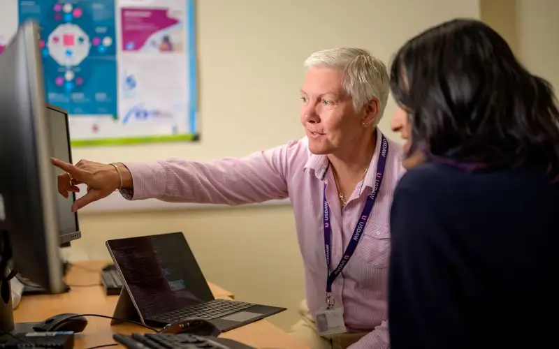 Two colleagues reviewing work on a monitor
