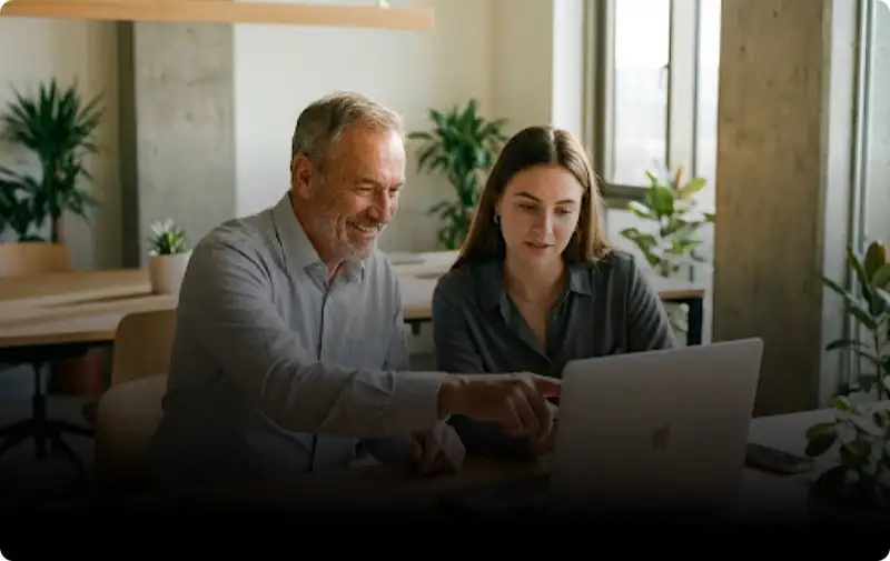 A trainer and a learner working at a laptop